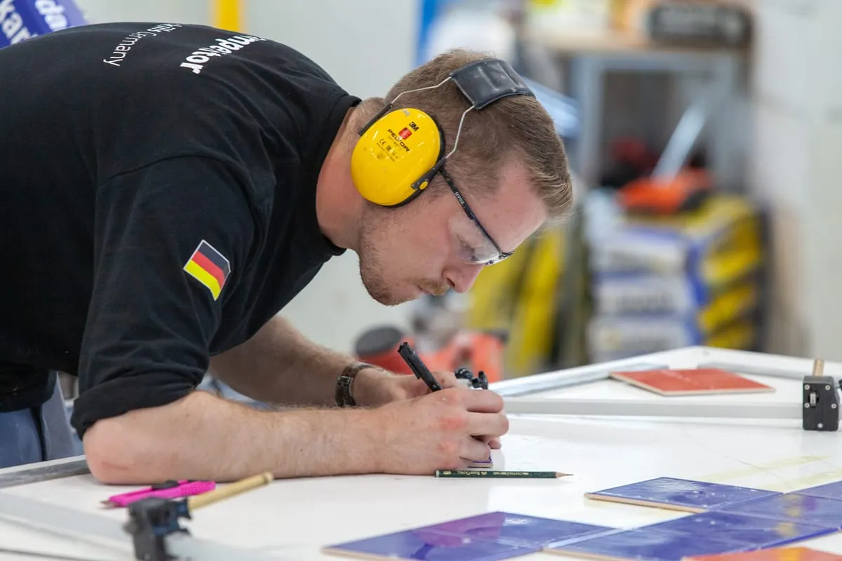 Fliesenleger Janis Gentner hochkonzentriert. Beim Verlegen der Fliesen geht es um Millimeter.