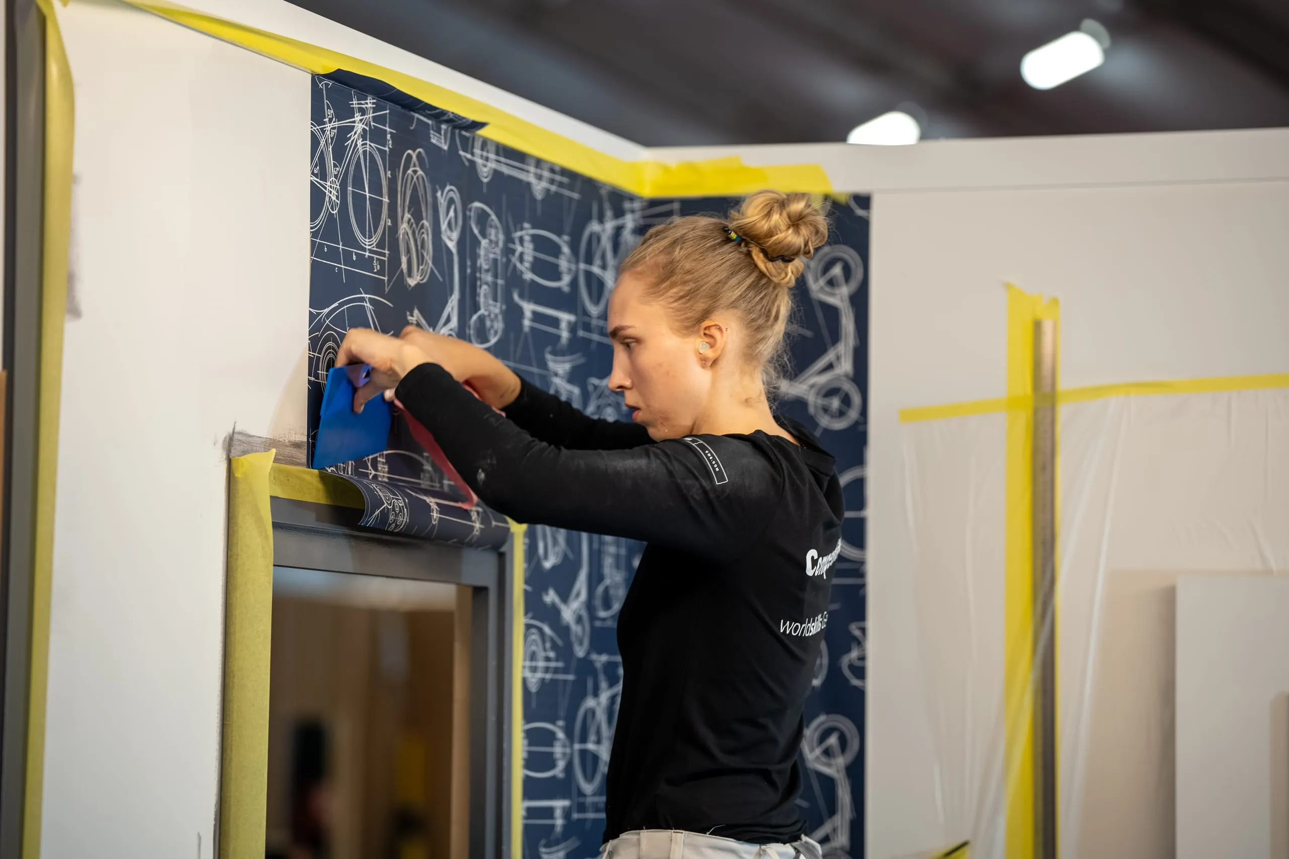 Malerin Freya Spitzer mit konzentriertem Blick auf die Tapete bei dem EuroSkills 2023.