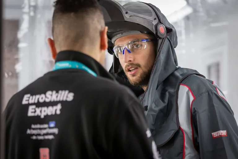 Fahrzeuglackierer Johannes Brandl in Absprache mit seinem Experten bei den EuroSkills 2023 in Danzig.