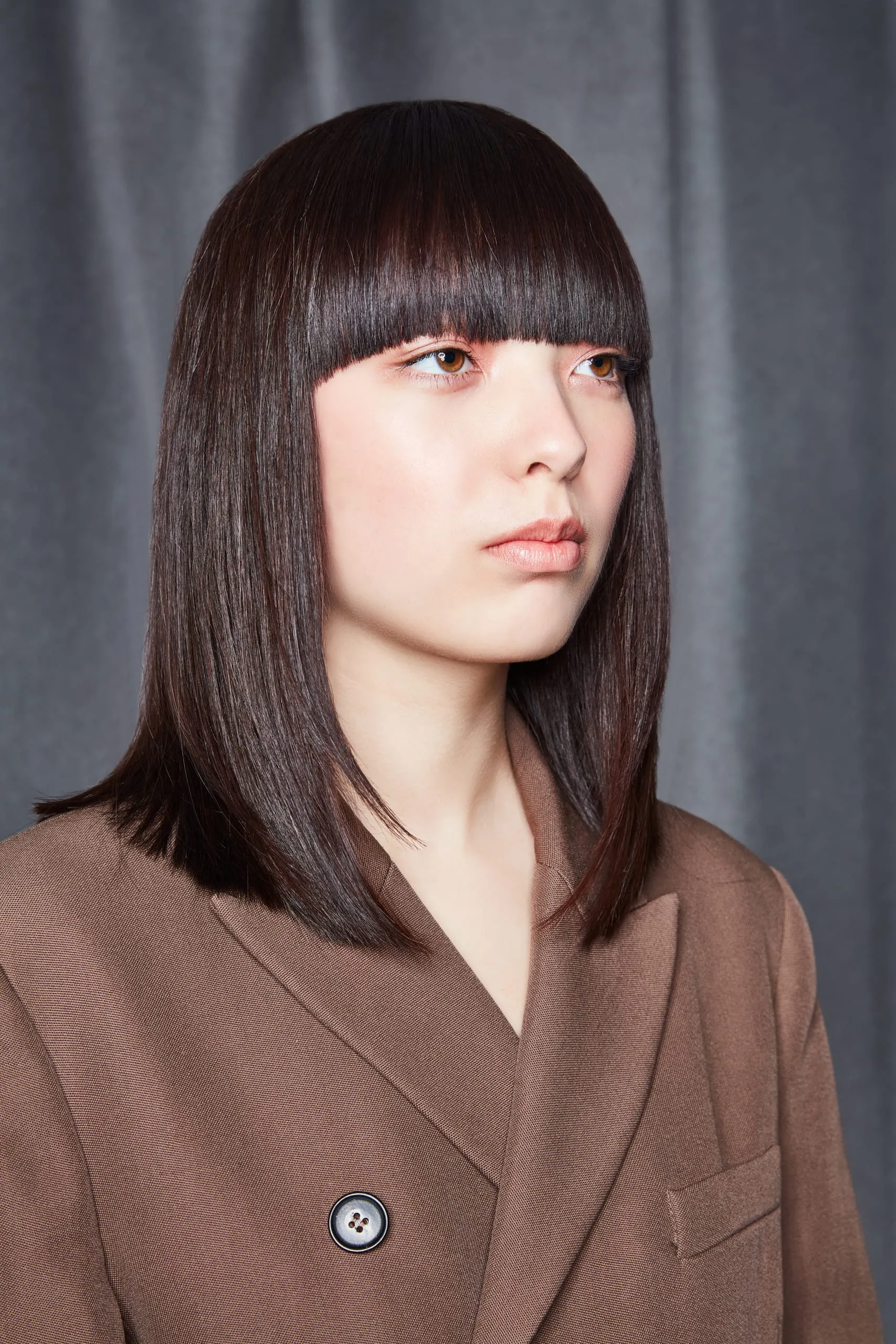 Balanced Bangs (Serie E1) Wie der Name schon sagt, lebt dieser halblange Look vom perfekt ausbalancierten geraden Pony. Kombiniert mit der exakt geschnittenen Kontur auf Schlüsselbeinlänge und einem super sleeken Finish ist Balanced Bangs ein understated, supermoderner Look. Die Stufung sorgt für Leichtigkeit und Flexibilität und der satte Zartbitter-Ton verleiht Tiefe und einen Hauch Drama.