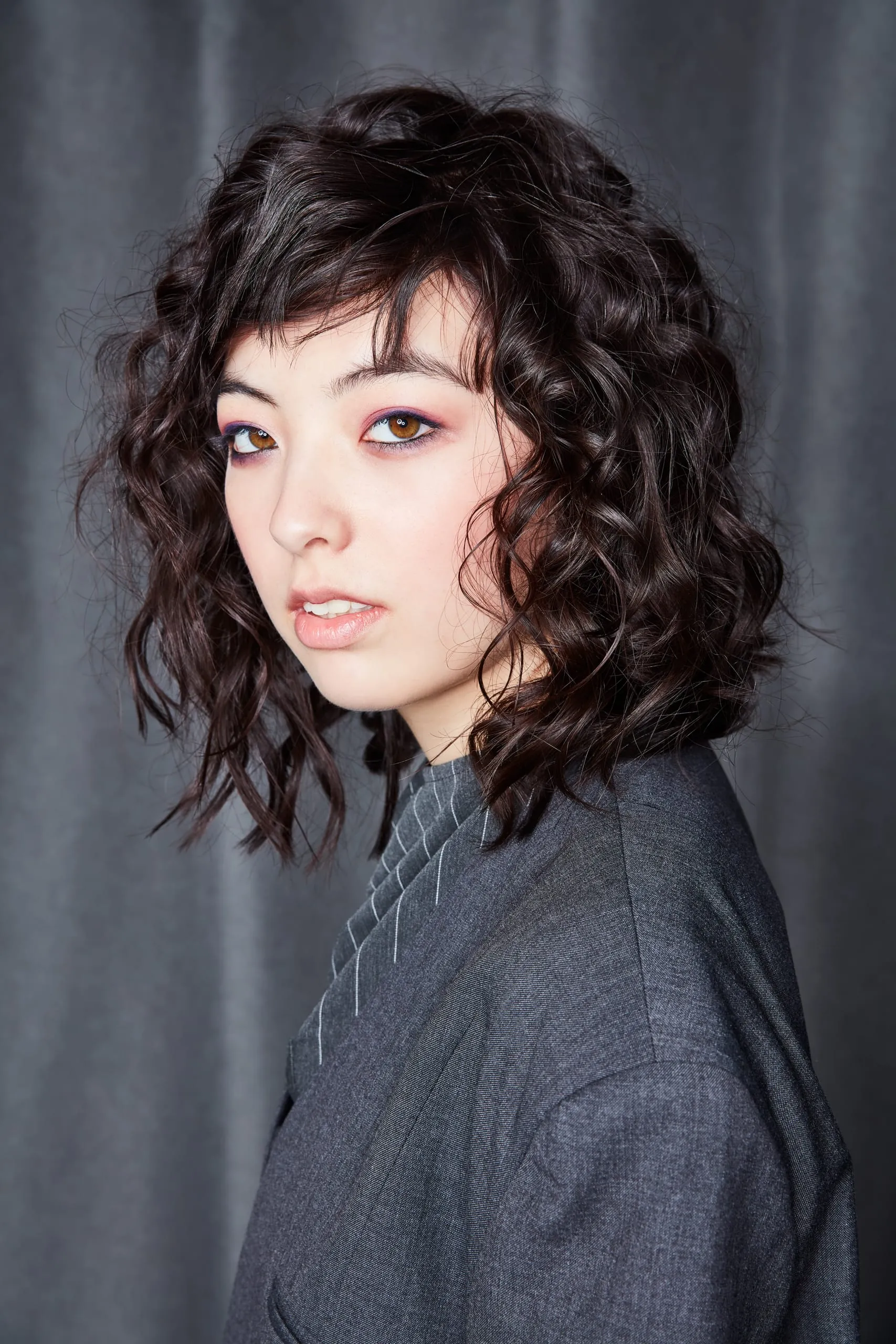 Curls Addict (Serie E2) Eine völlig andere Wirkung bekommt der Cut in der lockigen Variante. Die Haare werden mit dem Lockenstab geformt und dann mit einer Stylingcreme frisiert um nicht zu angestrengt zu wirken. Der lange, volle Pony wird zur Seite aus dem Gesicht gestylt. Die angesagteste Kombination für den Herbst und Winter.