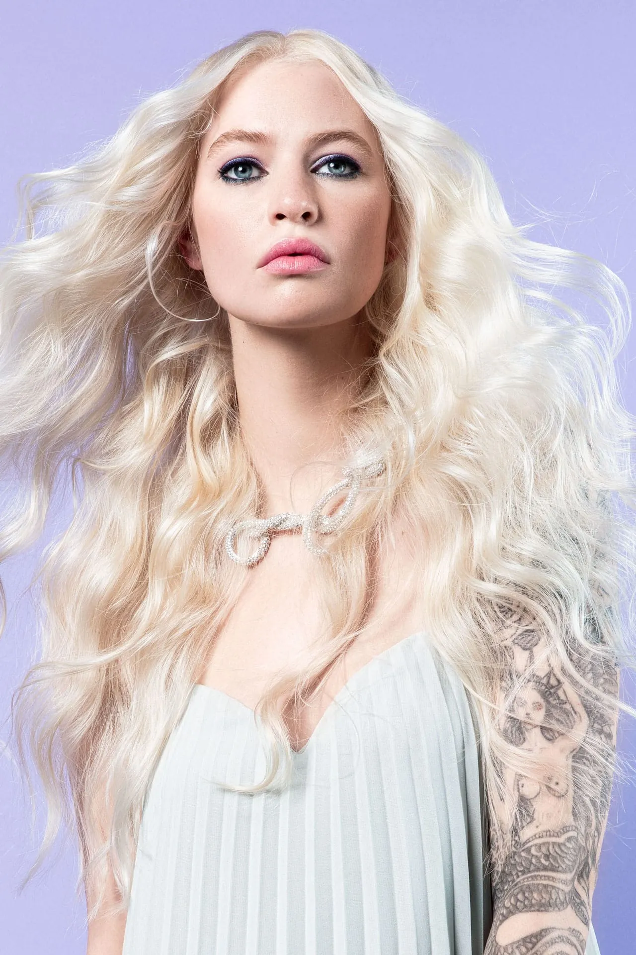 Wavy Pearl (Serie E2) Locker-leicht und ätherisch entführt dieser Locken-Look in die Glamourwelt der 70er Jahre. Die Haare werden über einen Lockenstab gedreht und anschließend mit den Händen ausfrisiert. Trockenes Haarspray sorgt für das perfekte Finish.