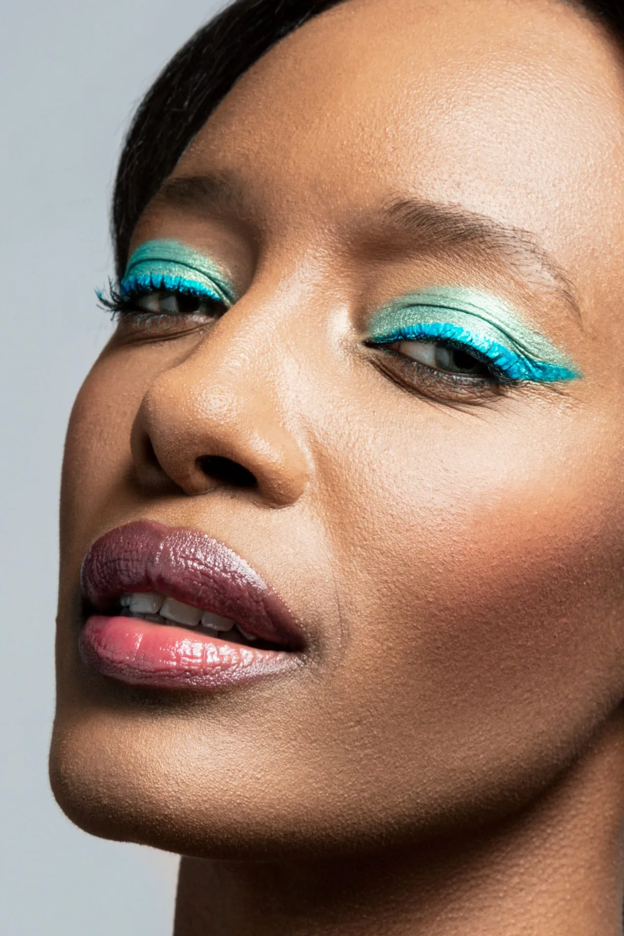 Beauty Look: Colourful Flowers (Serie F2) Ein mintgrüner Lidschatten mit goldenem Schimmer auf dem beweglichen Lid lässt die Augen strahlen. Noch stärker in den Fokus setzt sie ein geschwungener Eyeliner in Türkis. Schwarzer Kajal auf der unteren Wasserlinie und kräftig schwarz getuschte Wimpern verleihen dem Look mehr Ausdruck. Dezentes Rouge in Pink und braunroter Lipgloss unterstreichen den coolen Sommerlook.