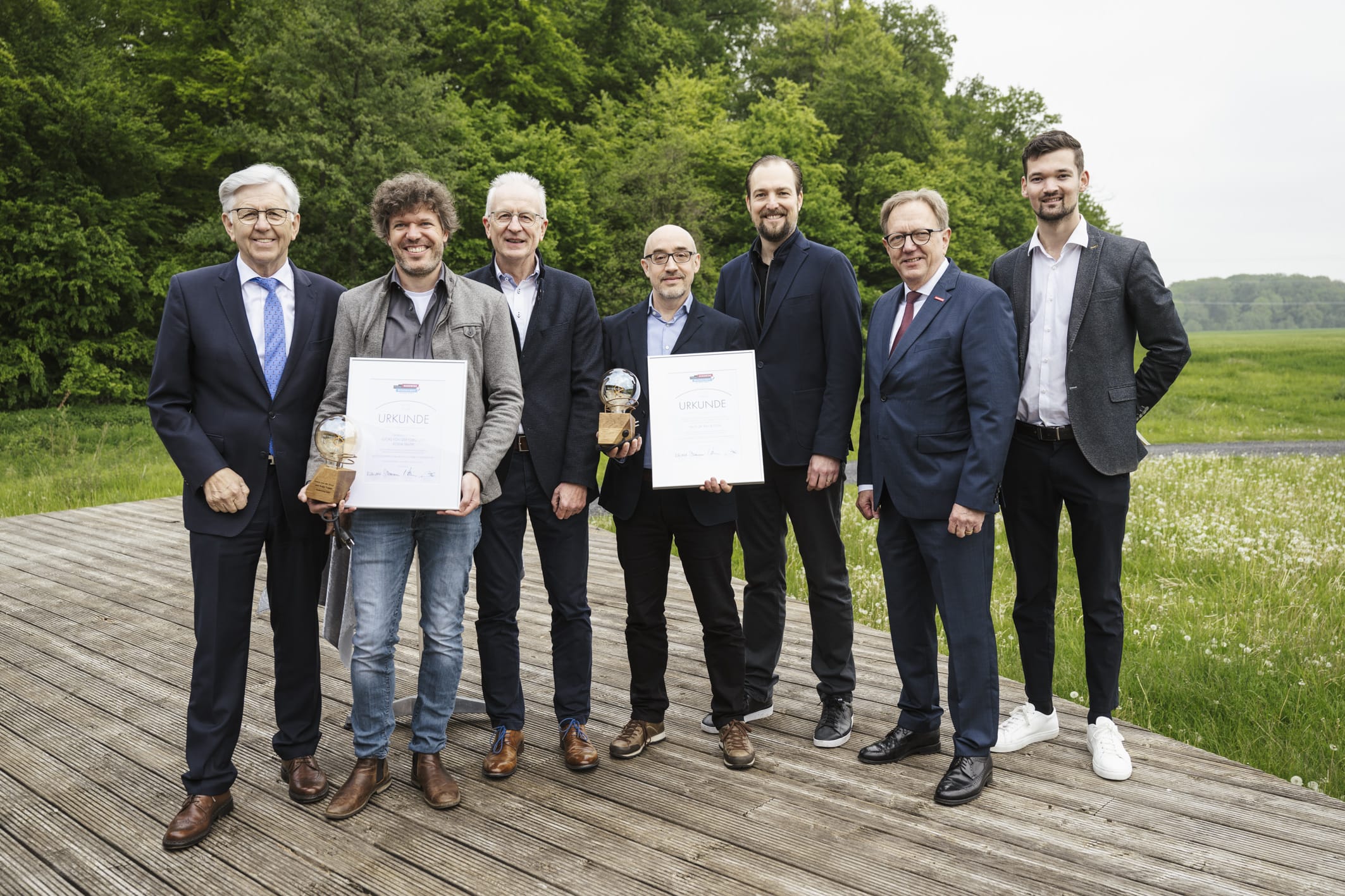 Trophäe und Urkunde: Rodja Trappe (2. v. l.) und Prof. Dr. Ralf Bloch (4. v. l.) freuen sich im Handwerksbetrieb über den renommierten Preis, den die Seifriz-Delegation im Gepäck hatte.