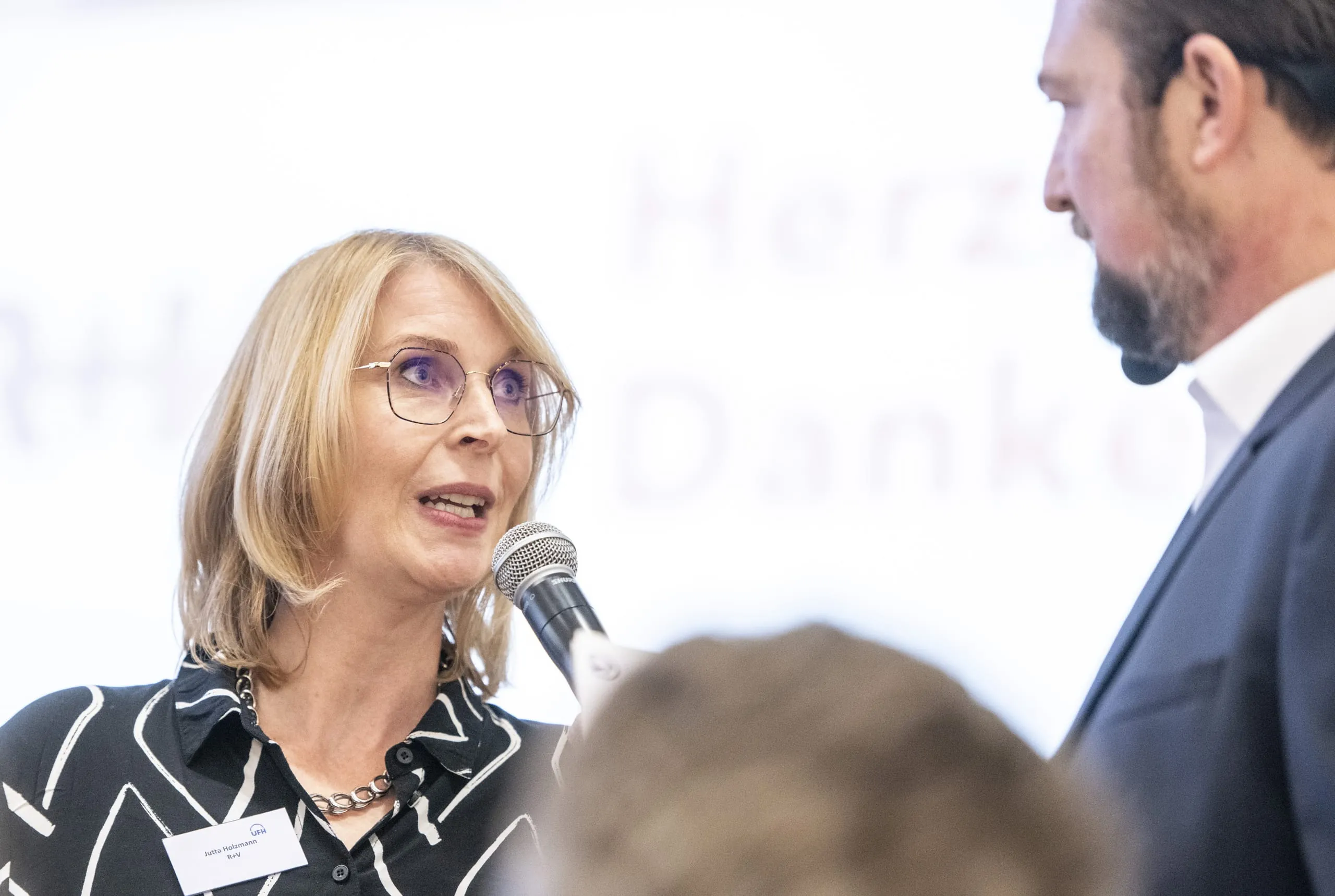 Die zweite Laudatio des Abends hält Jutta Holzmann, Leiterin Strategische Projekte R+V Versicherung – hier im Gespräch mit Moderator Patrick Neumann.
