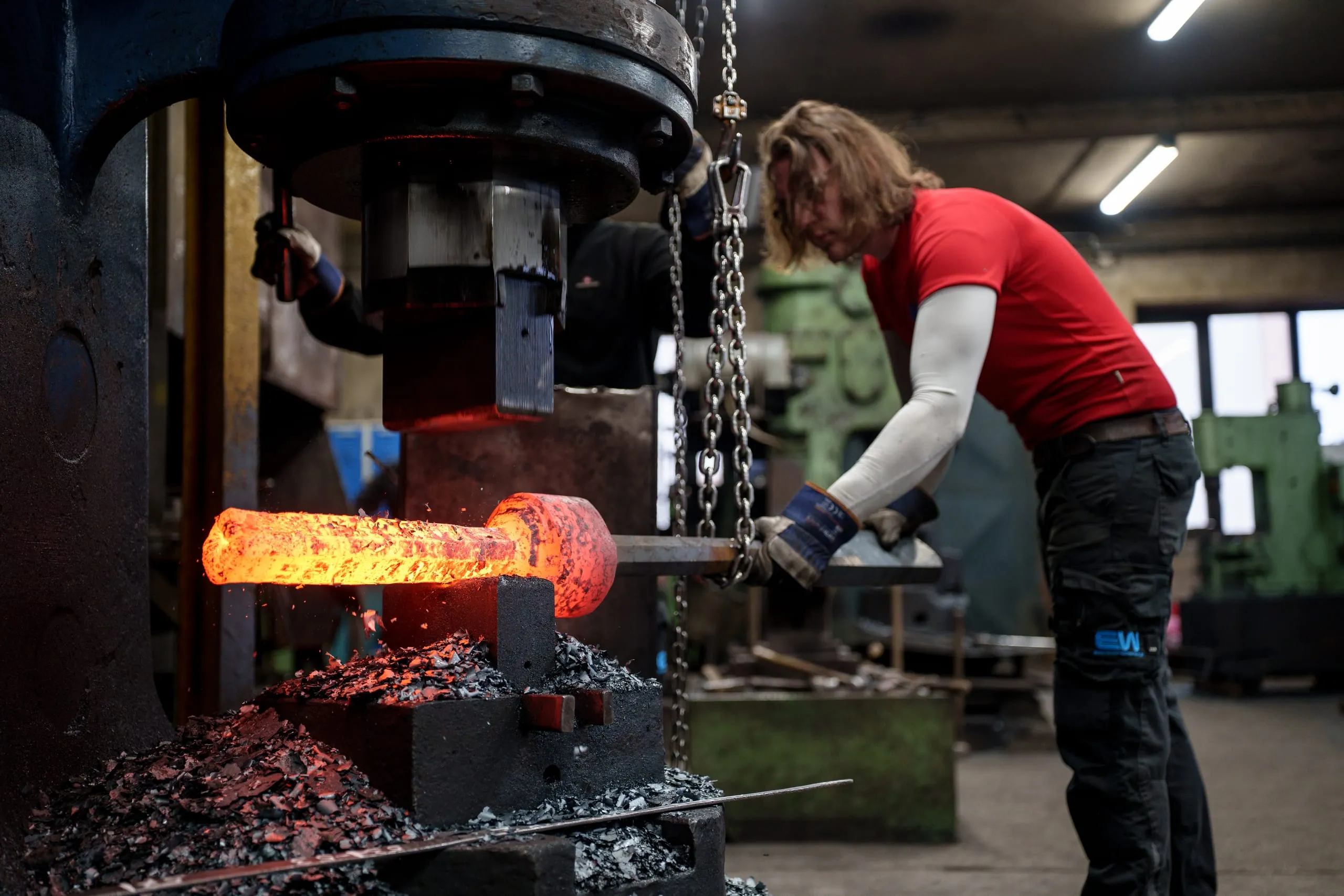 Ein Schmied an der Hammerschmiede formt mit präziser Handwerkskunst einen großen Glockenklöppel für die Notre-Dame.