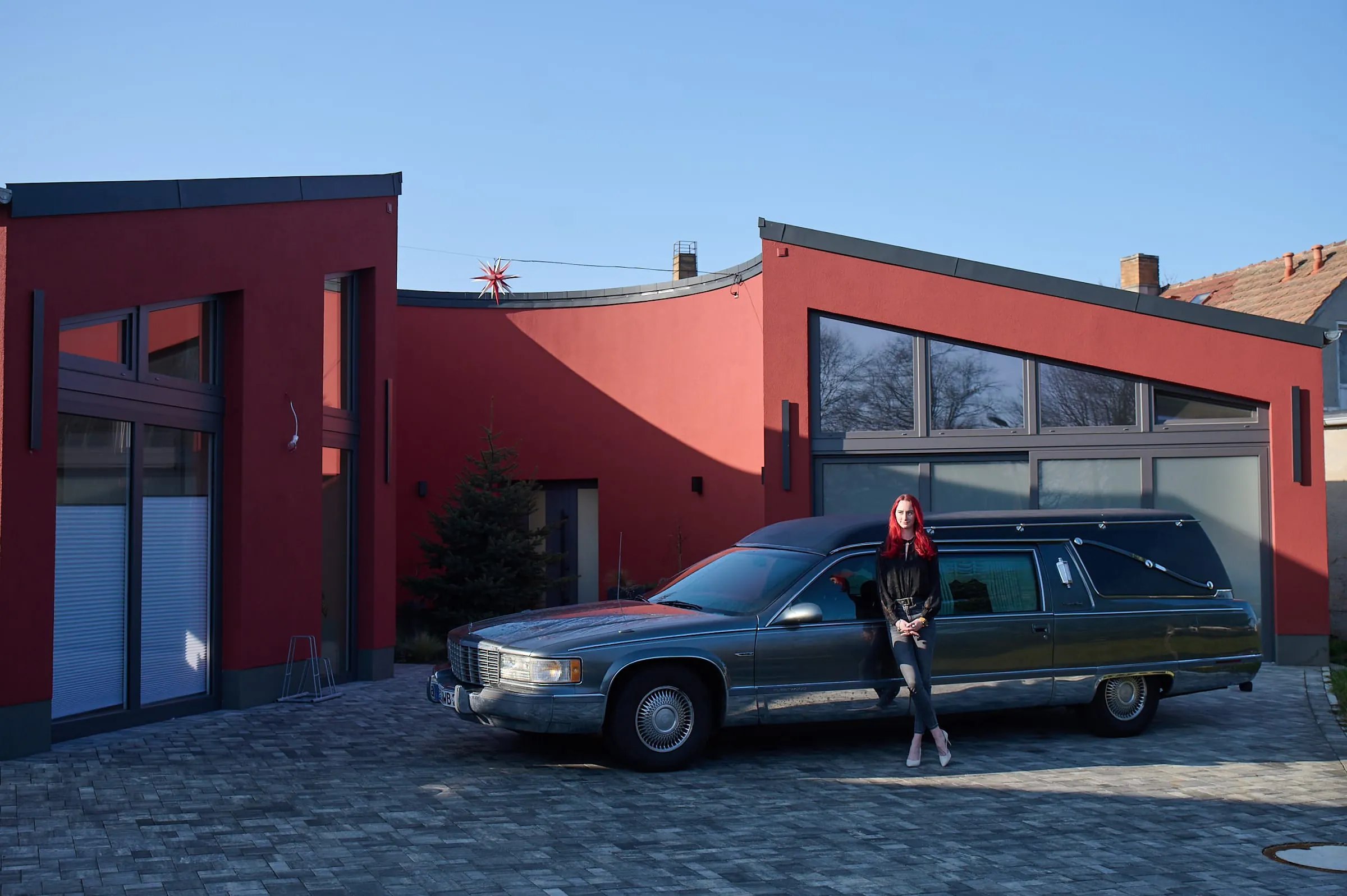 Bestattungsfachkraft Annabell Wandelt steht mit ihrem Cadillac vor ihrem Bestattungshaus.