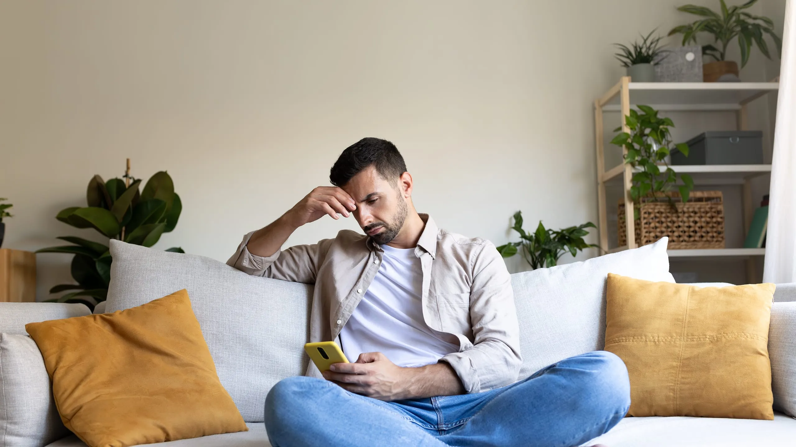 Ein Mann sitzt auf dem Sofa und schaut in sein Smartphone. Das verbildlicht den Sofa-Test, der Handwerker-Websites und die Lupe nimmt und deren Internetauftritt verbessern soll.