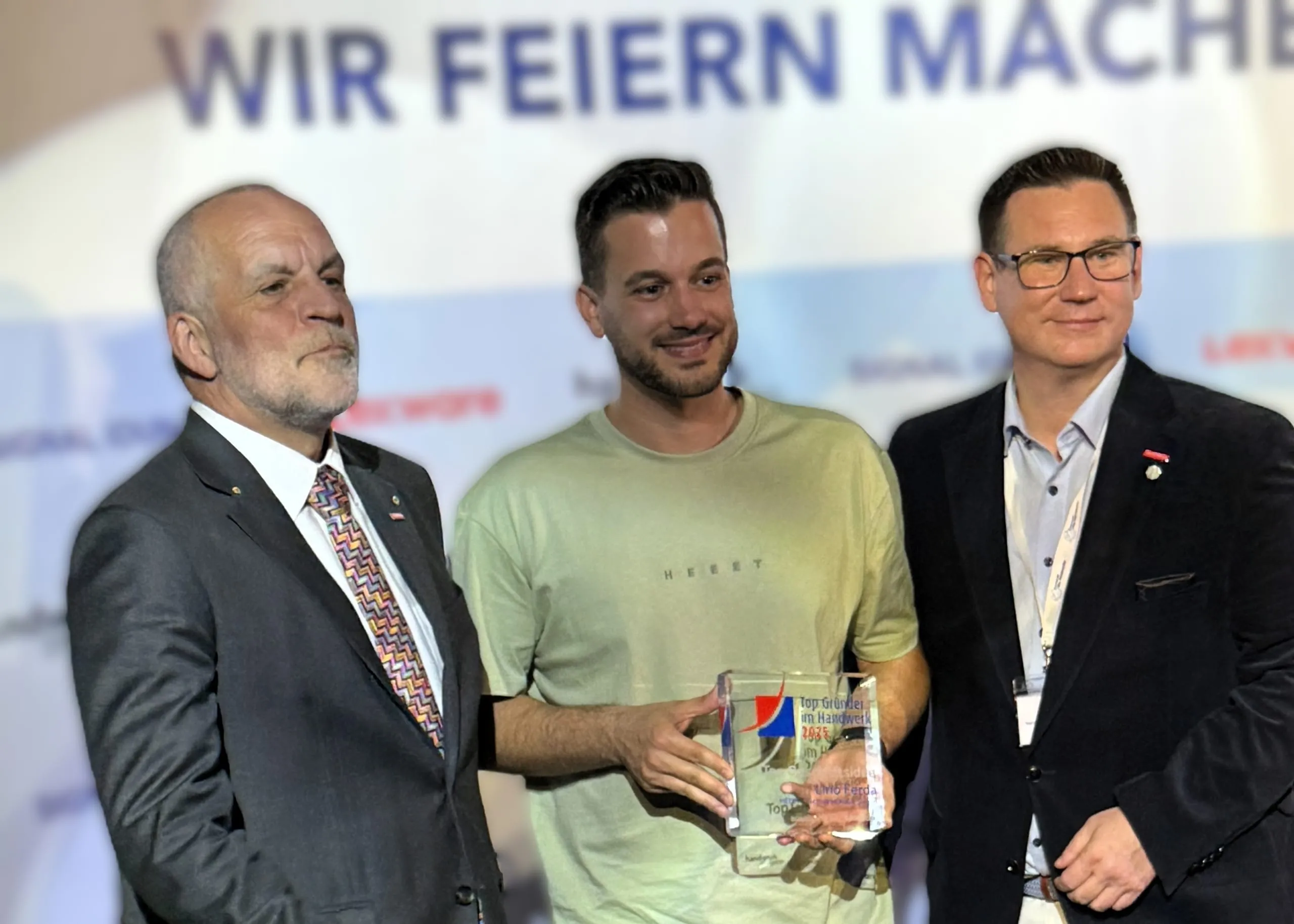 Und jetzt nochmal offizielle Siegerbilder vor der Logowand: Den Anfang macht Lino Ferda, der für seine „Top Geschäftsidee“ geehrt wurde. Umrahmt wird er hier von Markus Renfordt (li.), Präsident der Handwerkskammer Südwestfalen, in der HEET heimisch ist, und Kay Schlüter (re.), Abteilungsleiter Betriebsberatung des Kammerbezirks.