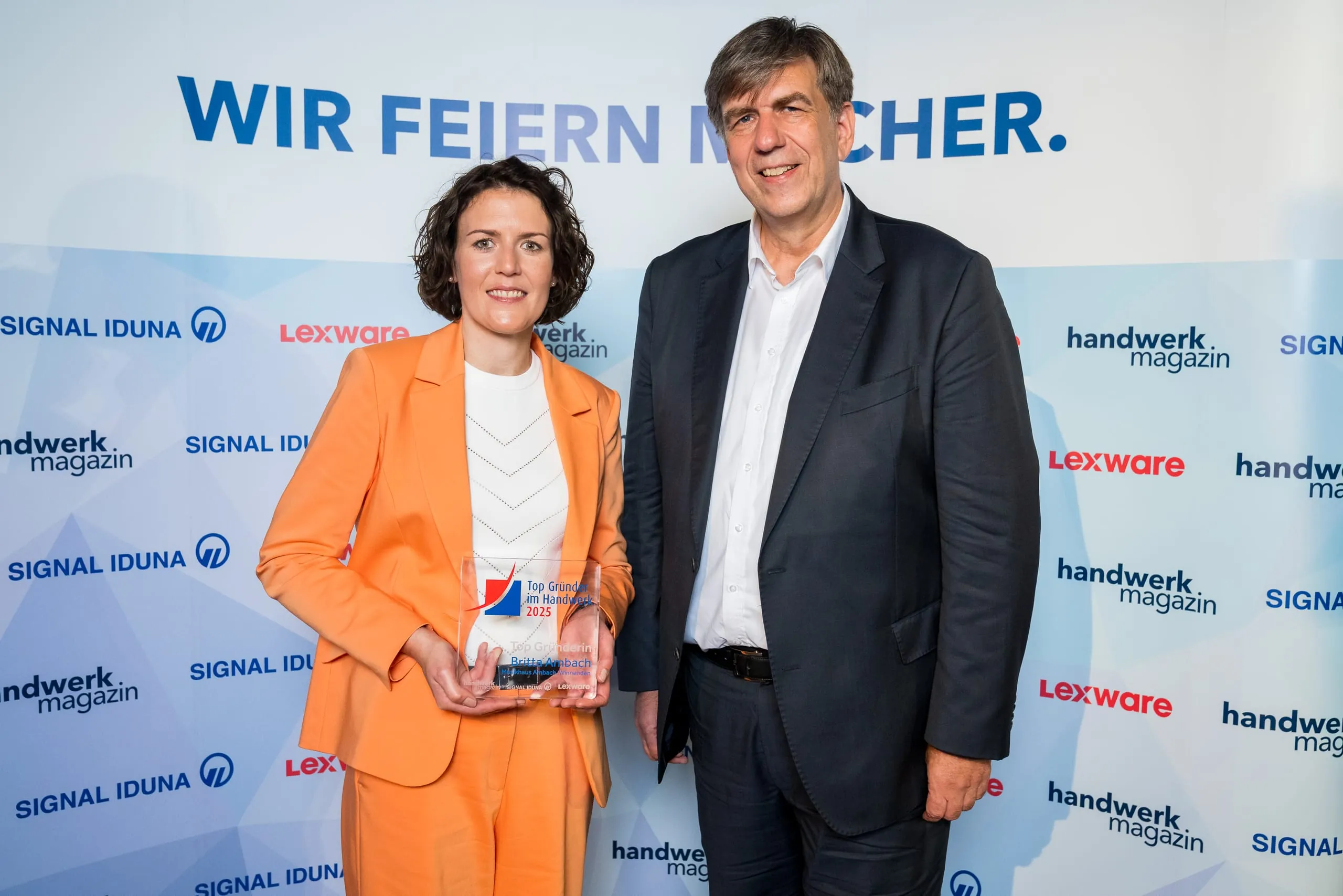 Das zweite Gewinnerbild vor der offiziellen Logowand: „Top Gründerin“ Britta Ambach (li.) und Holzmann-Medien-Verlagsleiter Jan Peter Kruse.