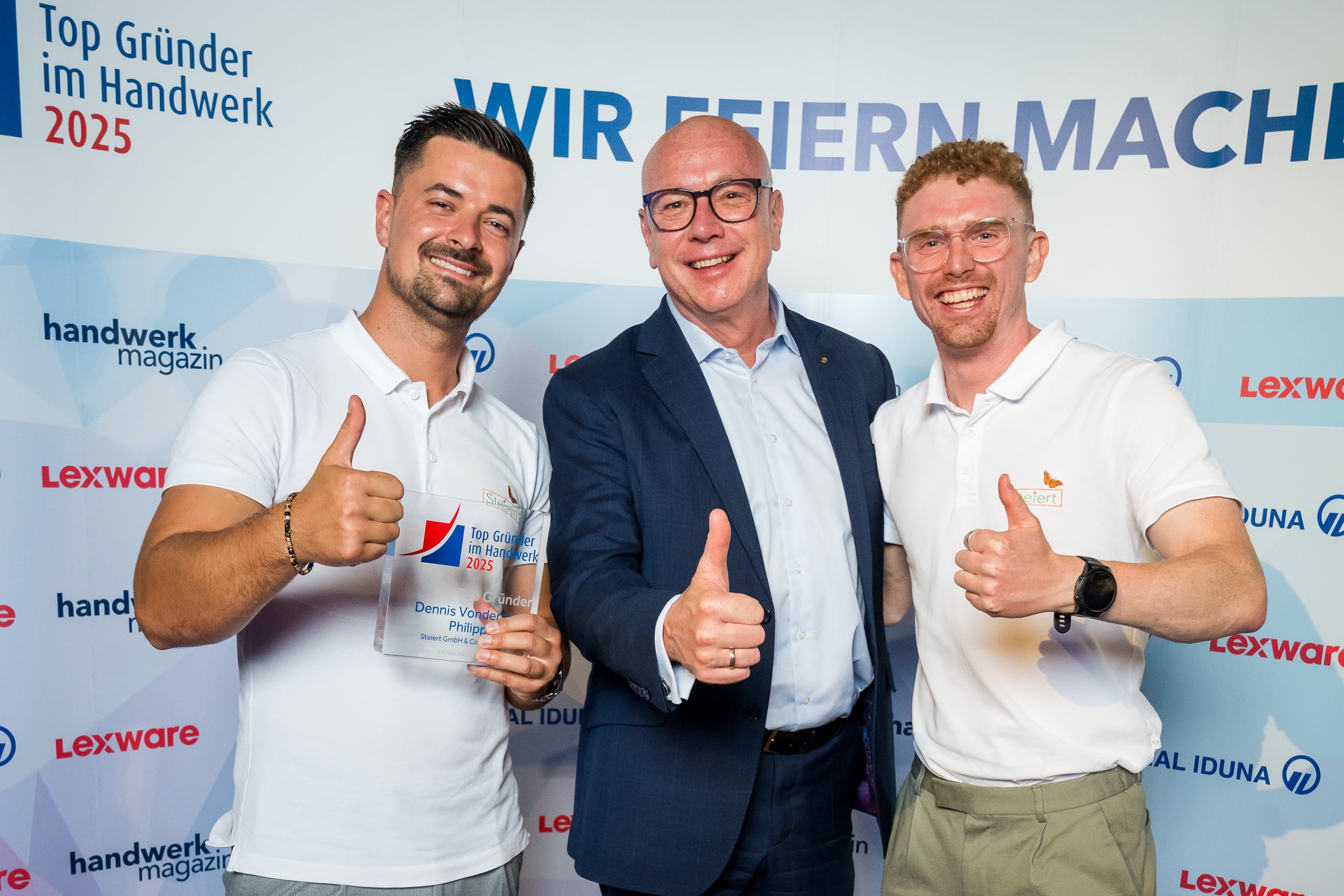 Daumen hoch: Das dritte Siegerfoto vor der Logowand zieren die „Top Gründer“ Dennis Vonderstraß (li.) und Philipp Steiert (re.) gemeinsam mit Torsten Uhlig, CEO der Signal Iduna Gruppe.