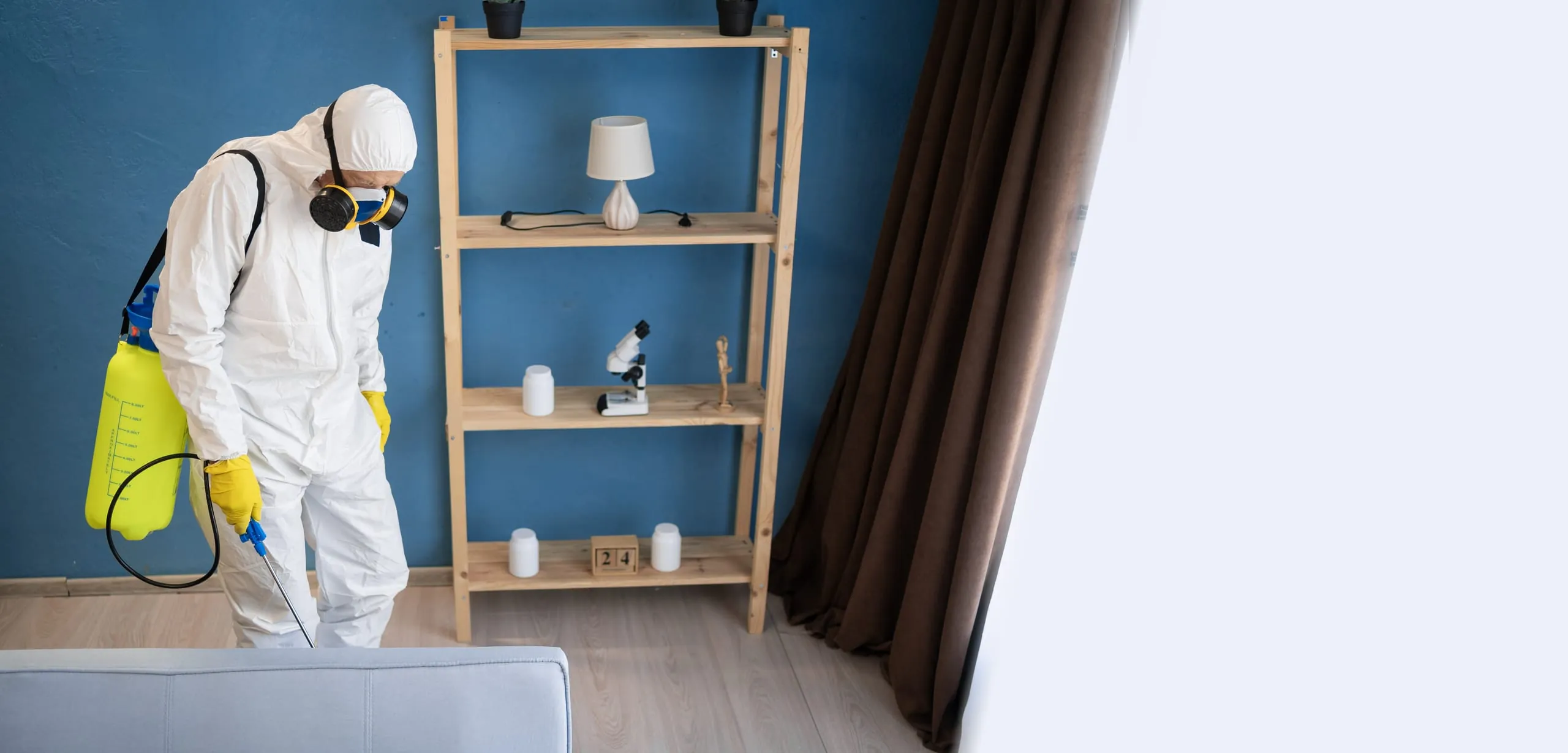 Mann im Schutzanzug bekämpft Schädlinge in einer Wohnung.