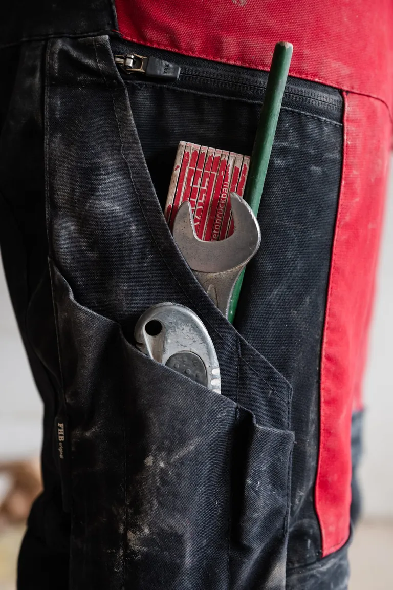 Die lange FHB-Hose tr&auml;gt Mario Hug auch bei 35 Grad. Im Meterfach immer dabei: Meterstab, Bleistift, Cuttermesser &ndash; und der 19er-Gabelringschl&uuml;ssel, ohne den er nicht aus dem Haus geht.