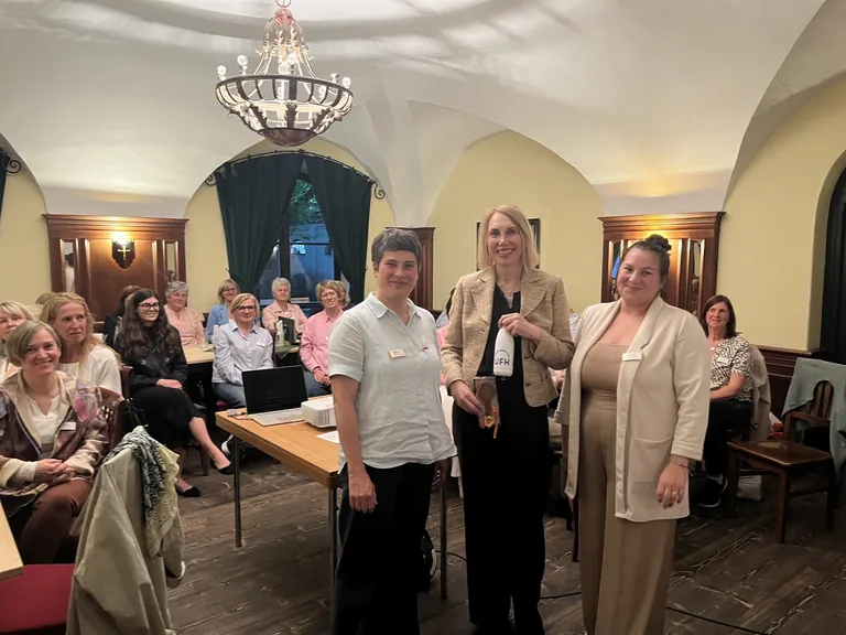 Drei Damen im Zentrum, v.l.n.r.: Maria Daxauer, Speakerin Alexandra Lindner, Laura Kavas. Im Hintergrund die UFH-Mitglieder des Landesverbands.